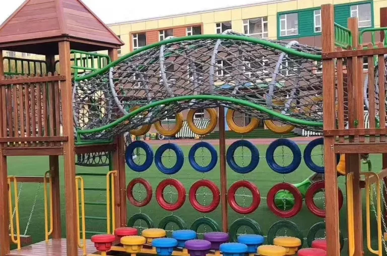 Playground Equipment Manufacturer | Indoor Soft Play & Custom Outdoor Playgrounds | Xinjiu Timber play posts and wooden structures beside a rope connection