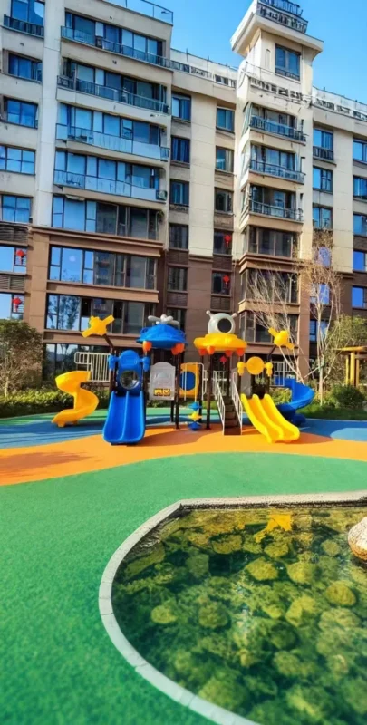 Playground Equipment Manufacturer | Indoor Soft Play & Custom Outdoor Playgrounds | Xinjiu Blue and yellow playground surrounded by a landscaped residential courtyard