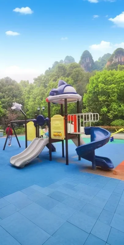 Playground Equipment Manufacturer | Indoor Soft Play & Custom Outdoor Playgrounds | Xinjiu Outdoor play tower and slide with trees and distant hills