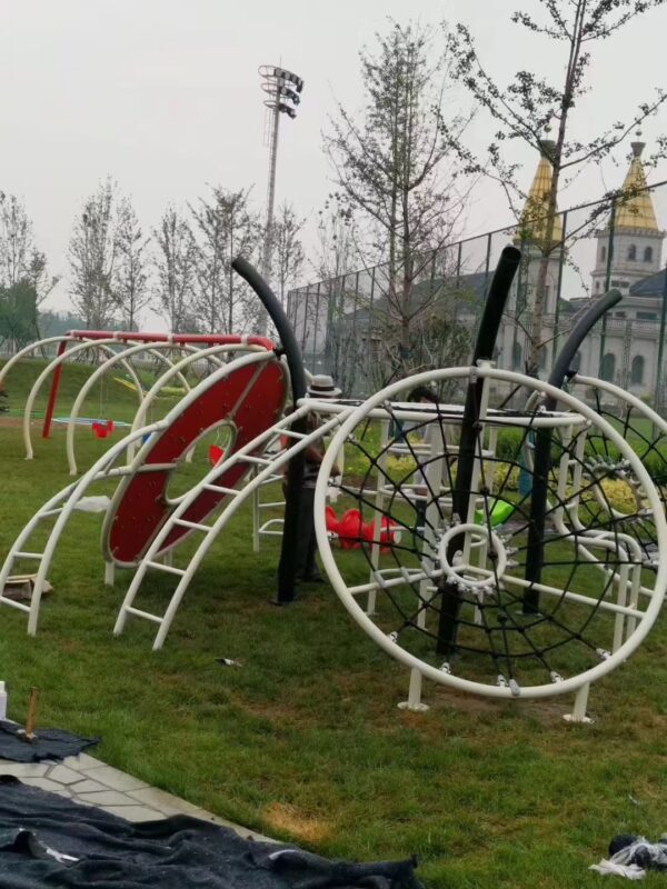 Indoor & Outdoor Playground Equipment | Soft Play, Custom Structures & Slides | Xinjiu Circular frame playground with a three dimensional rope climbing net and red climbing panel